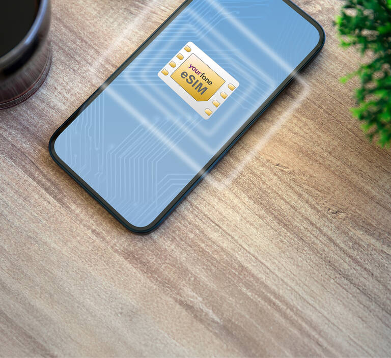 Handy auf Tisch mit yourfone eSIM Tarif auf dem Display
