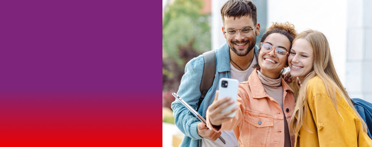 Zwei Frauen und ein Mann stehen lächelnd nebeneinander und schauen auf ihr Handy