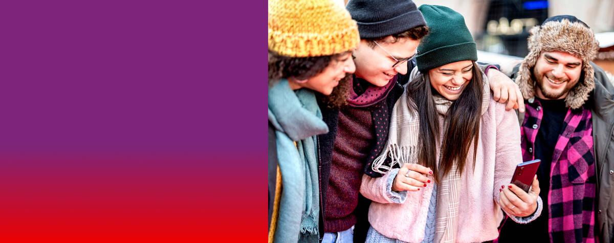 Drei Männer und eine Frau stehen lächelnd nebeneinander und schauen auf ihr Handy