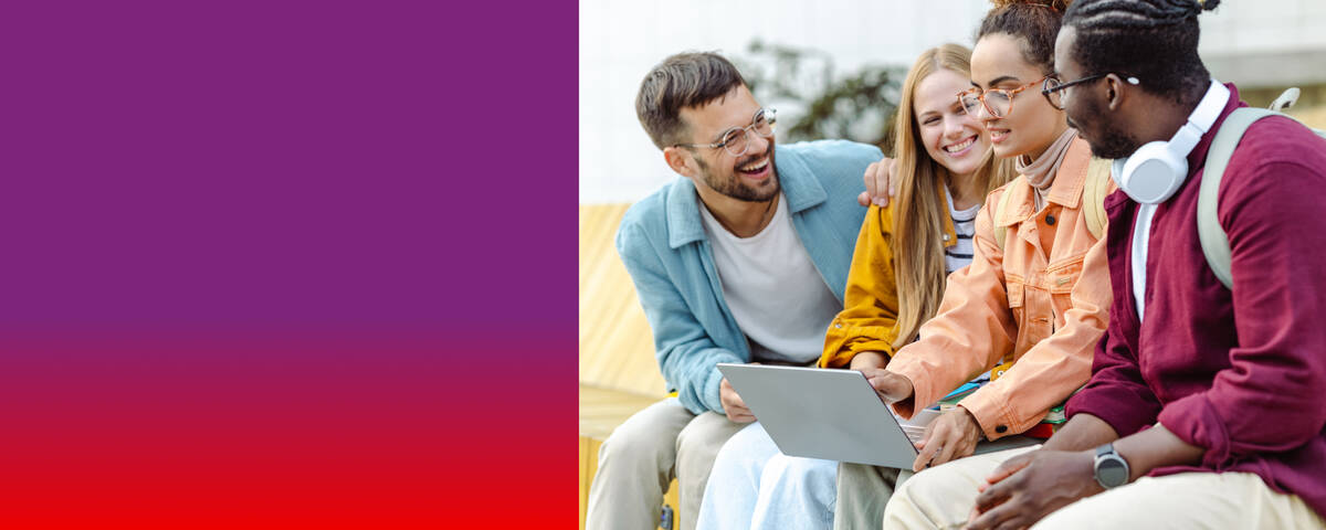 Vier Freunde lächeln während sie auf den Laptop schauen.