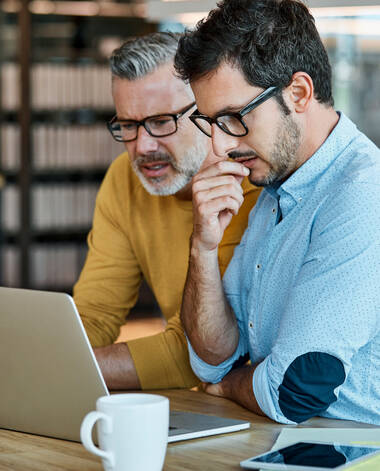Zwei Männer sitzen vor Laptop und ergreifen Sofortmaßnahmen nach dem Verlust des Handys