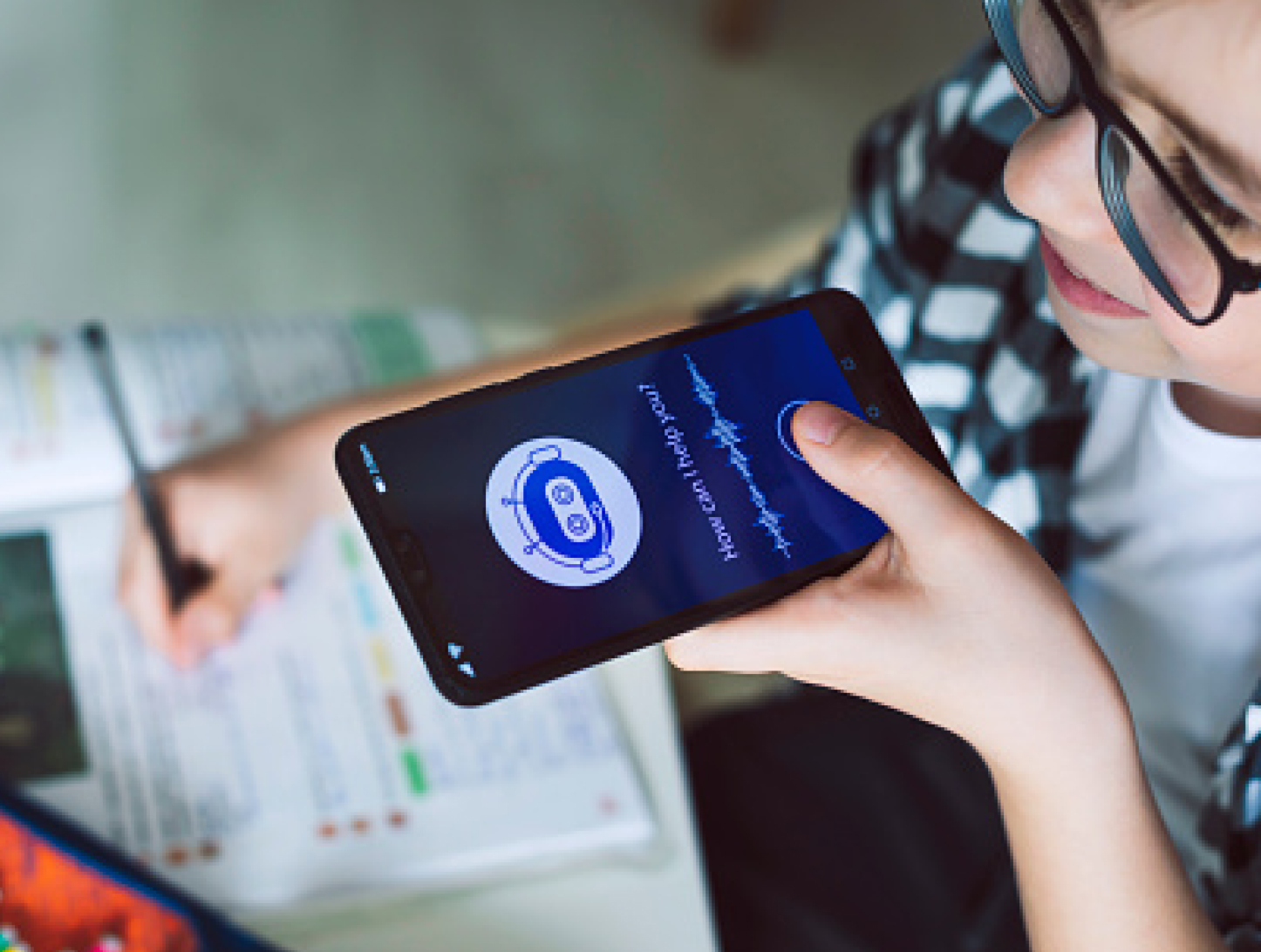 Junge Frau mit Brille spricht mit dem Sprachassistenten ihres Smartphones.